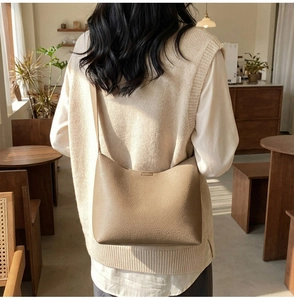 Lifestyle view of light brown pebbled leather shoulder bag in a warm cafe setting