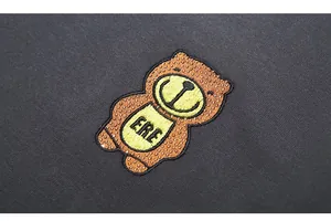 Macro detail of high-quality bear embroidery and rhinestones on a charcoal grey sweatshirt
