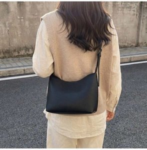 Outdoor shot of a black pebbled leather hobo bag with adjustable strap worn by a model