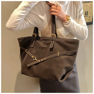 Deep brown oversized tote bag detail featuring metallic buckle straps and matte texture