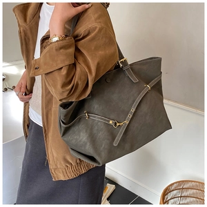 Detail of minimalist charcoal tote bag with frosted leather texture and golden hardware