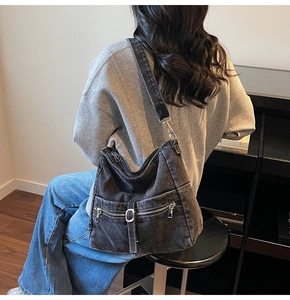 Detail of retro washed black denim shoulder bag with multiple functional zipper pockets