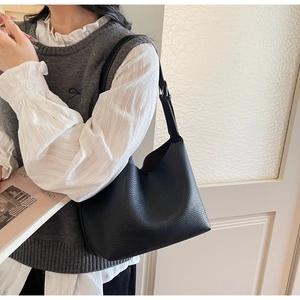 Detail of black lychee texture leather hobo bag with adjustable metallic buckle strap