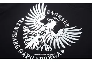 Close-up of metallic silver eagle emblem print on black cotton oversized streetwear t-shirt