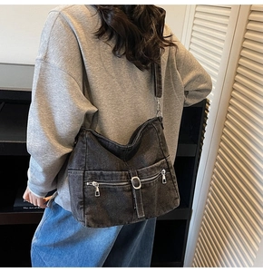 Detail of dark denim crossbody bag showing cargo pockets and metal buckles on a hobo design