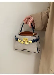 Detail of canvas handbag with navy leather trim and golden twist lock closure