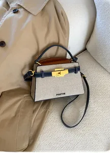 Detail of canvas mini bag with dark blue leather trim and golden twist-lock closure