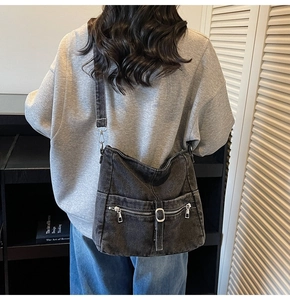 Detailed back view of a black denim crossbody bag with multiple pockets and metal hardware