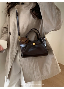 Detail of retro dark brown leather bag with golden H buckle and mini coin purse charm