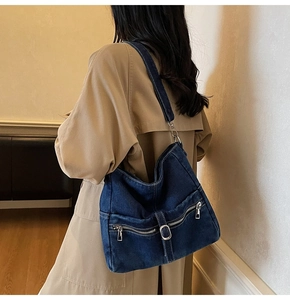 Detail of dark blue denim tote bag with silver zippers and belt buckle accents
