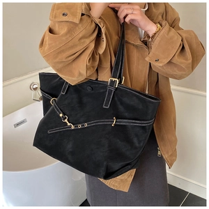 Black suede tote bag with contrast stitching and gold hardware shown on model
