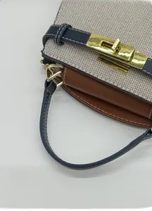 Close-up of golden clasp on canvas and leather handbag with contrast stitching detail