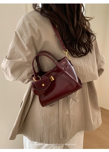 Detail of burgundy leather handbag with a matching small coin purse charm and gold hardware