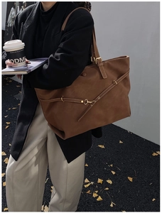 Detailed view of large brown leather tote bag with metallic buckle and vintage texture