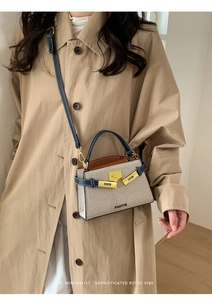Detailed close-up of a beige woven mini bag with navy leather trim and golden twist lock