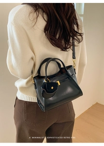 Detail view of black vintage leather tote bag with gold hardware and side pocket detail
