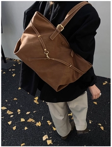 Outdoor shot of a large brown tote bag with gold hardware on an autumn street background