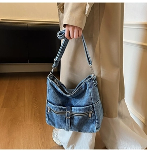 Detail of vintage washed blue denim hobo bag featuring multiple functional zippers