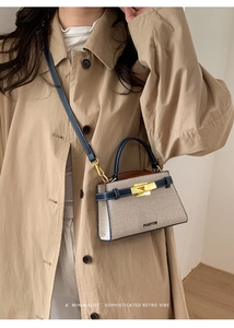 Detail of canvas and navy leather patchwork bag with gold twist lock on model