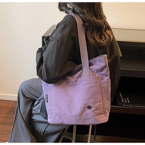 Detail view of purple canvas tote bag with thick strap and side brand label
