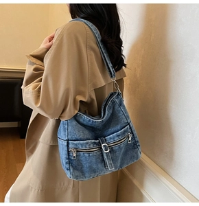 Detail of vintage blue denim tote bag with dual zipper pockets and metal buckles