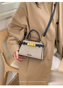 Detail of a minimalist beige woven handbag with blue leather trim and a gold twist lock