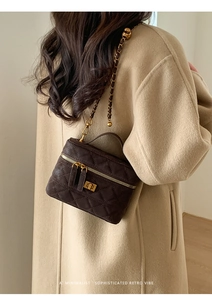 Detail of coffee brown quilted crossbody bag with gold chain and dual zipper accents
