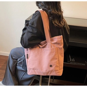Detail of pink nylon tote bag showing side pockets, woven strap and CHUANGMI brand tag