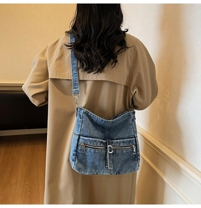 Detail of blue washed denim tote bag with functional zipper pockets and adjustable strap