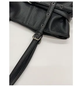 Detail of black litchi leather tote featuring metal eyelets and silver buckle strap