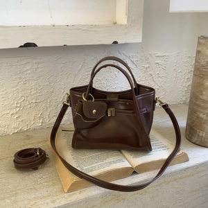 Detail of vintage dark brown handbag with mini flap charm and adjustable shoulder strap