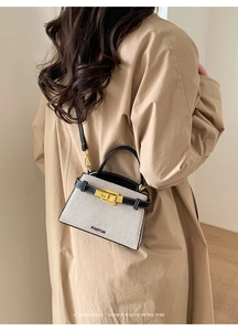 Close-up of cream tweed handbag with black leather trim and golden twist lock