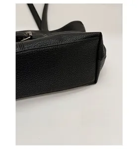Detail view of the wide base design on this black lychee pattern leather tote bag