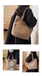 Detail of minimalist khaki large tote bag featuring side brand label and wide woven strap