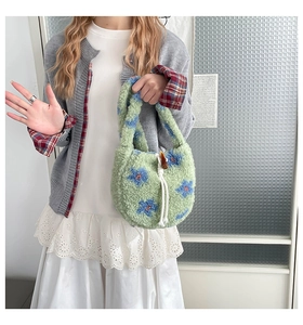 Détail du sac à main en peluche vert avec motifs floraux bleus et cordon de serrage