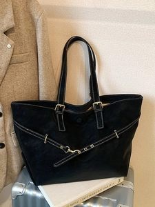 Minimalist black oversized tote bag with crossover straps and gold hardware detail