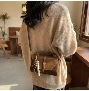 Détail d'un sac à main marron vintage avec fermoir en métal rétro et pompon perlé