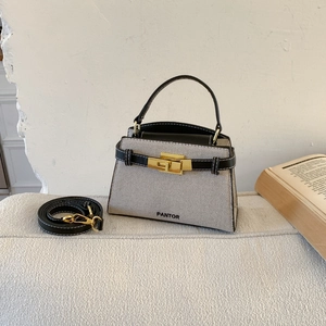 Detail of beige canvas and black leather stitching with gold clasp on a handbag