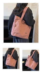 Detail of pink nylon tote bag showing wide shoulder strap and spacious front pocket