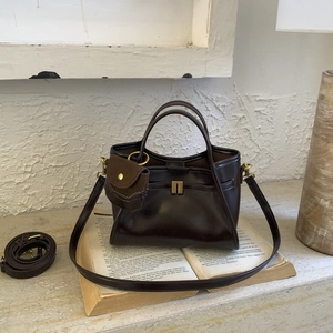 Detail view of deep coffee vintage tote bag with small hanging pouch on a book