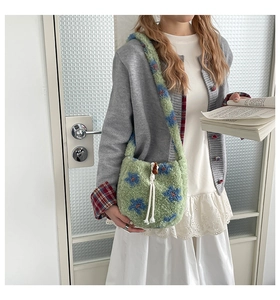 Détail du sac bandoulière en peluche verte avec motif floral bleu et cordon de serrage