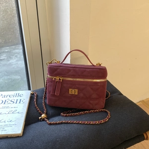 Close-up of vintage burgundy quilted vanity bag with gold chain strap on soft cushion