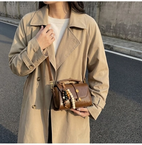 Détail du sac vintage en cuir marron avec perles en bois et texture lisse au fini huilé