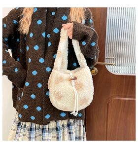 Détail d'un sac bandoulière en peluche avec motif floral, bouton bascule et anse tressée