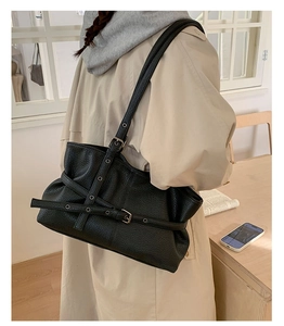 Detail of black lychee grain leather tote bag with stylish buckle and metal eyelets