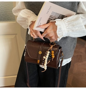 Gros plan sur un sac bandoulière vintage marron avec texture craquelée et perles bois