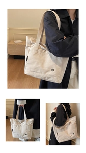 Detail of off-white canvas tote bag featuring front pocket and round metal logo accent