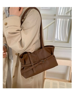 Detail of brown lychee texture leather shoulder bag with vintage buckle on beige coat