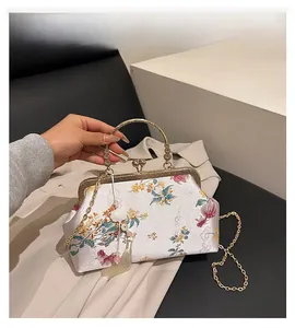 Detail of white satin handbag with floral embroidery and golden metal handle