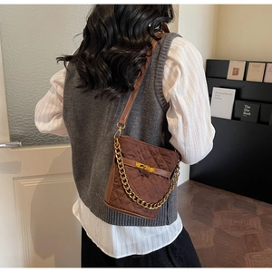 Détail d'un sac seau matelassé marron avec chaîne dorée et bandoulière sur modèle